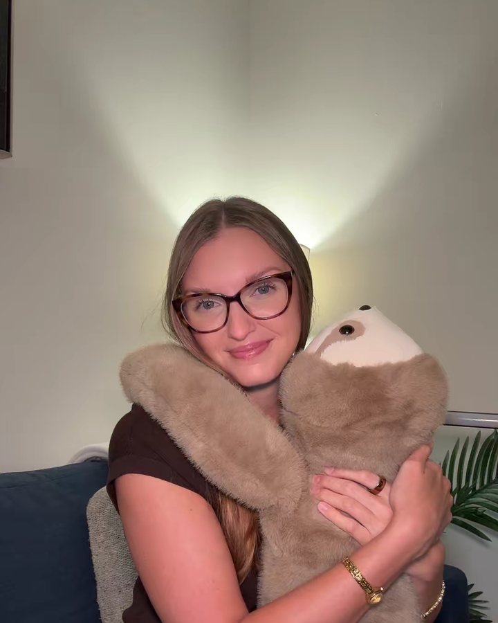 Kalli, a mental health therapist, smiling as she hugs a weighted sloth
